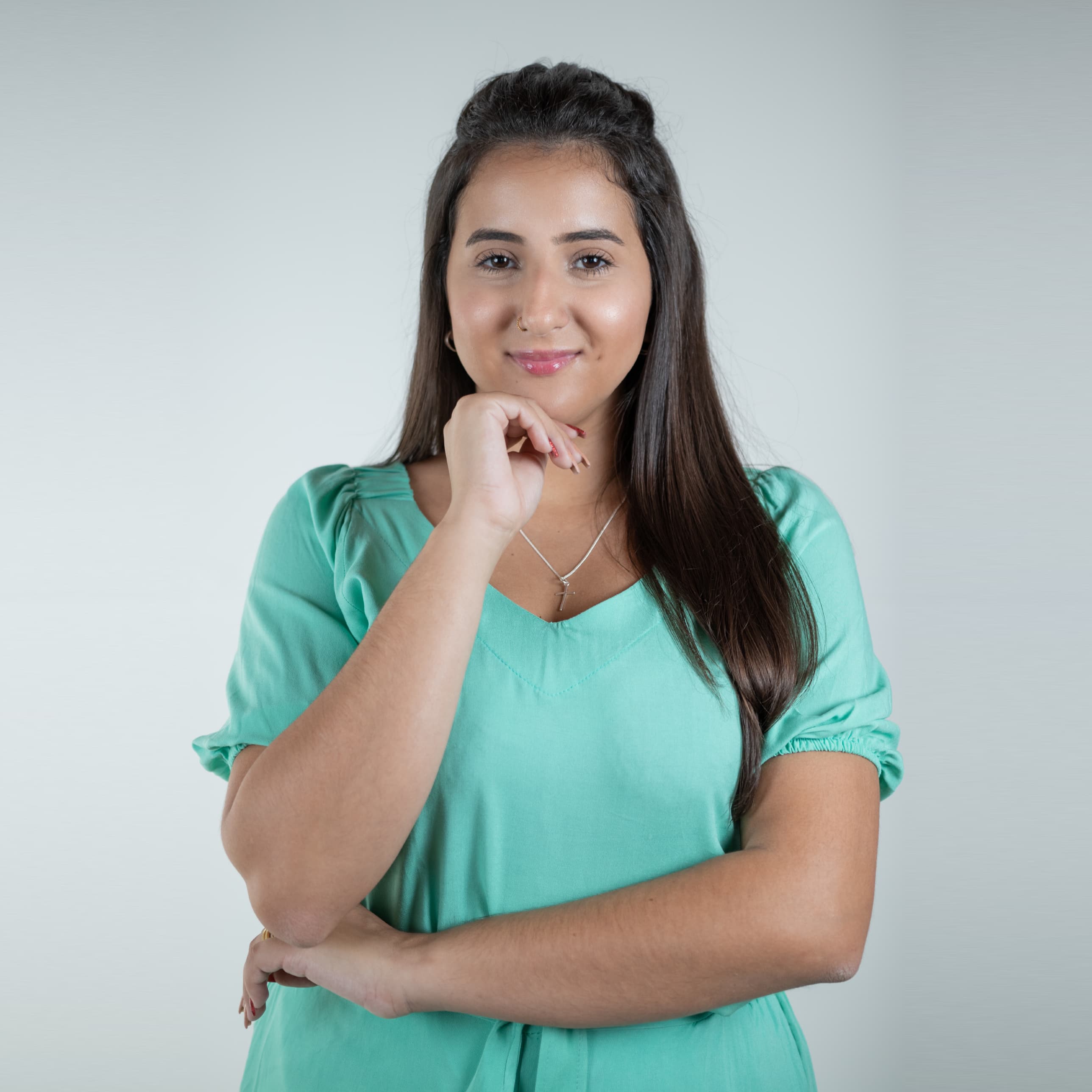 Any Medola smiling, wearing a teal blouse with her hand resting on her chin
